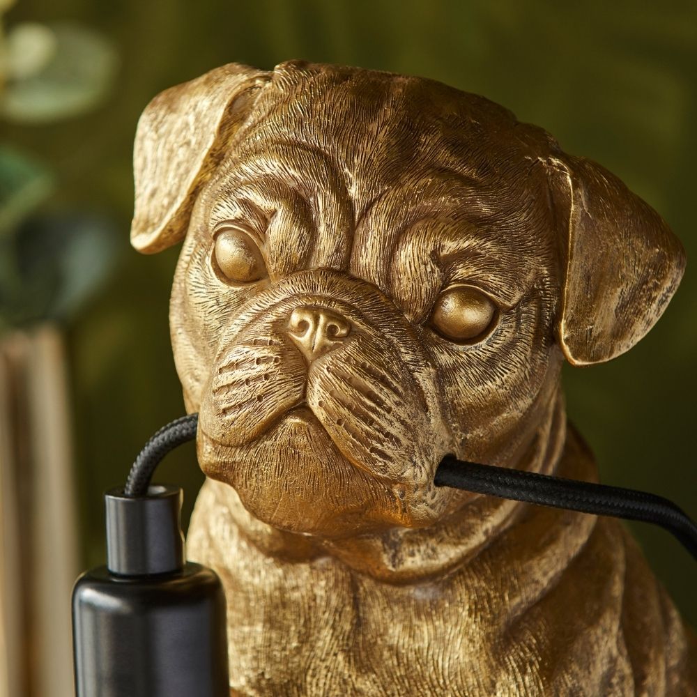 Close-up of gold pug resin lamp showing detailed textured finish and cable held in mouth, highlighting craftsmanship and decorative appeal.