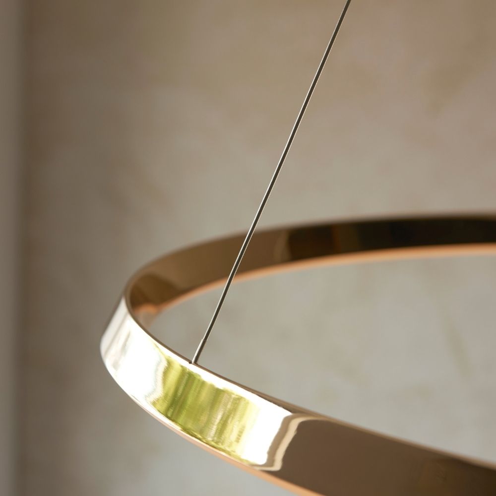 Detailed view of suspension wires and gold frame of modern LED ring ceiling pendant light.
