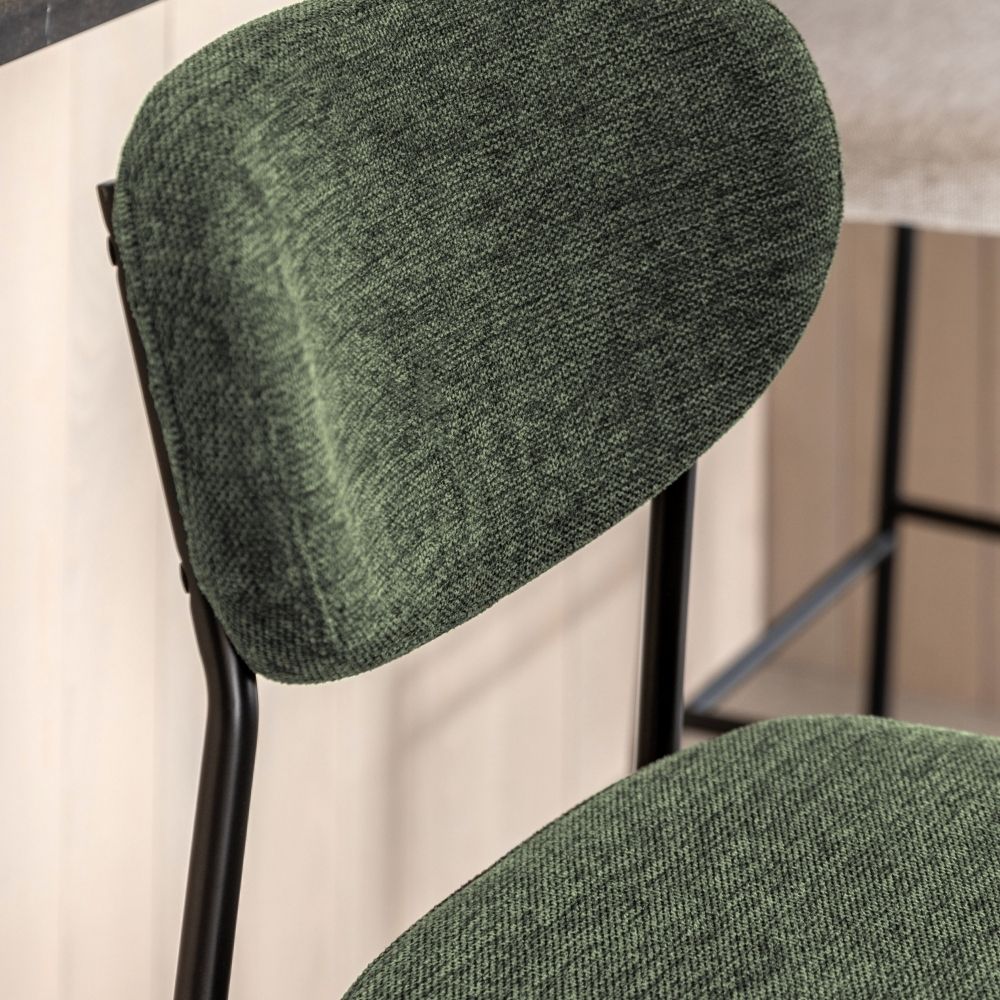 Close-up of a green fabric upholstered bar stool backrest showing textured weave and black metal frame.