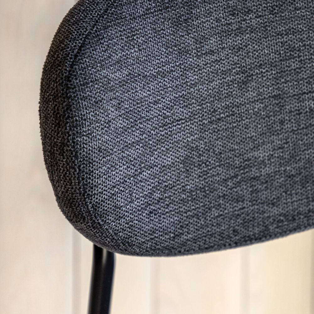 Detailed close-up of the grey upholstered backrest on a bar stool, highlighting the woven fabric texture and black metal support.