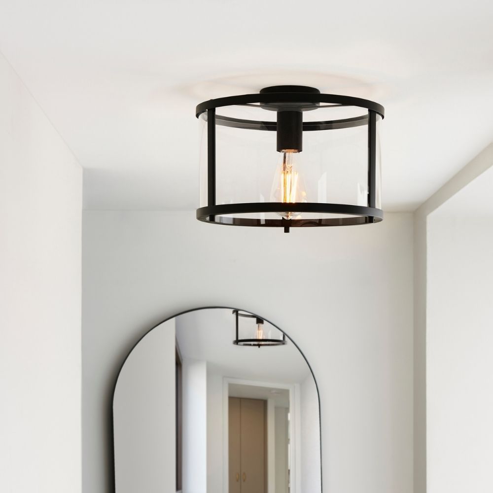 Black semi flush cage ceiling light installed in a minimalist hallway interior with mirror and neutral decor.