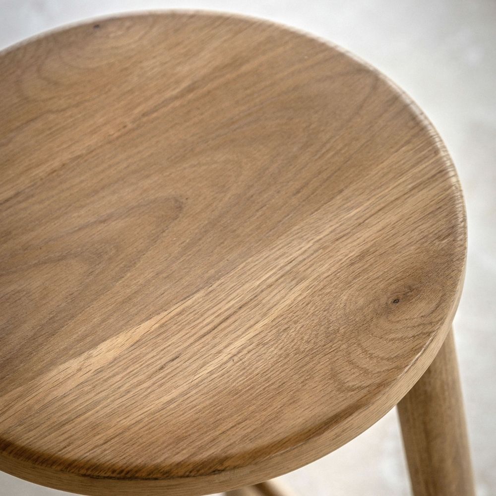 Close-up of a light oak wooden bar stool seat showing natural wood grain and smooth rounded edges.