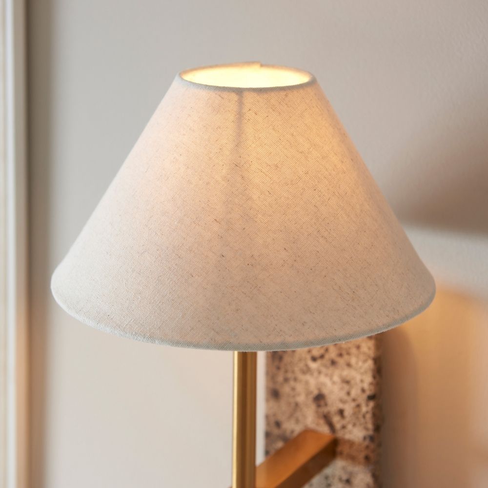 Close-up of linen lampshade on wall light emitting a soft warm glow, highlighting fabric texture and ambient lighting effect.