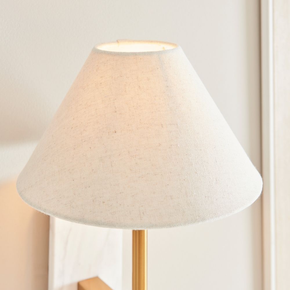 Close-up of linen lampshade on wall light showing fine fabric texture and soft warm illumination.