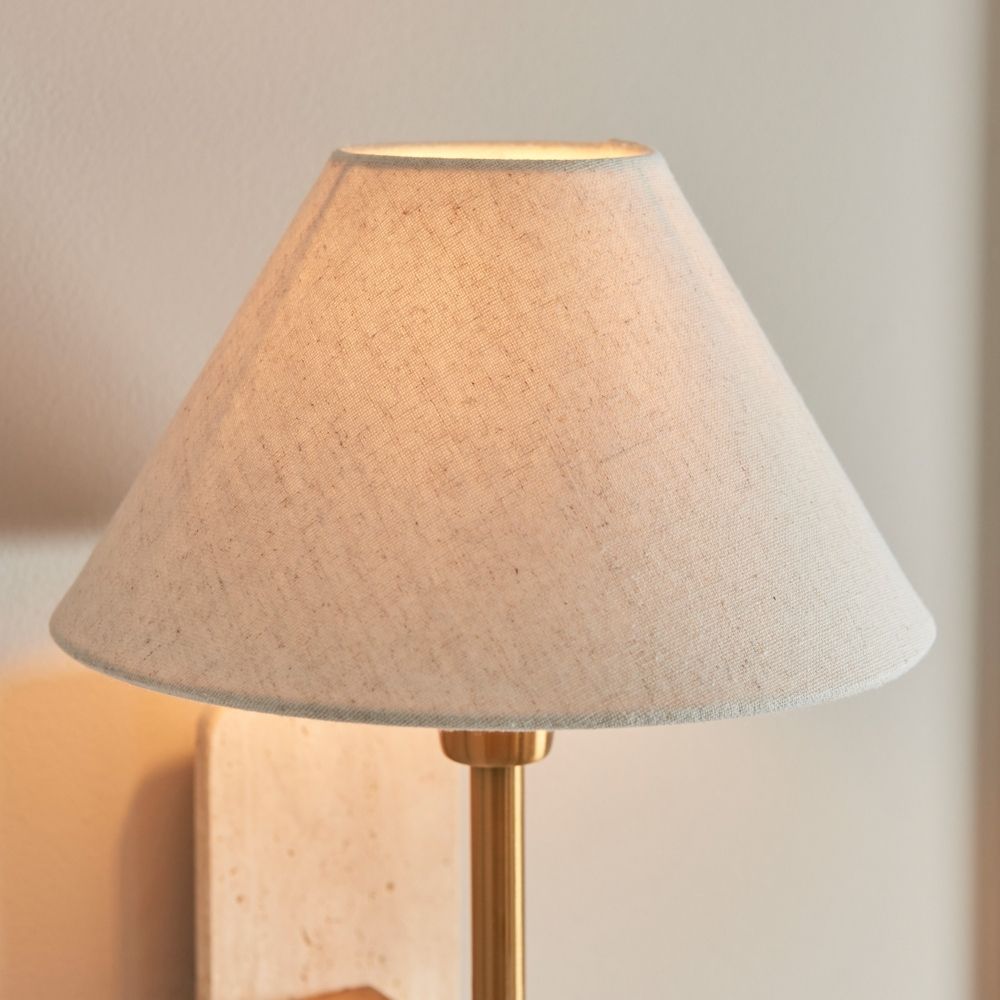 Close-up of linen lampshade on wall light showing soft fabric texture and warm diffused illumination.