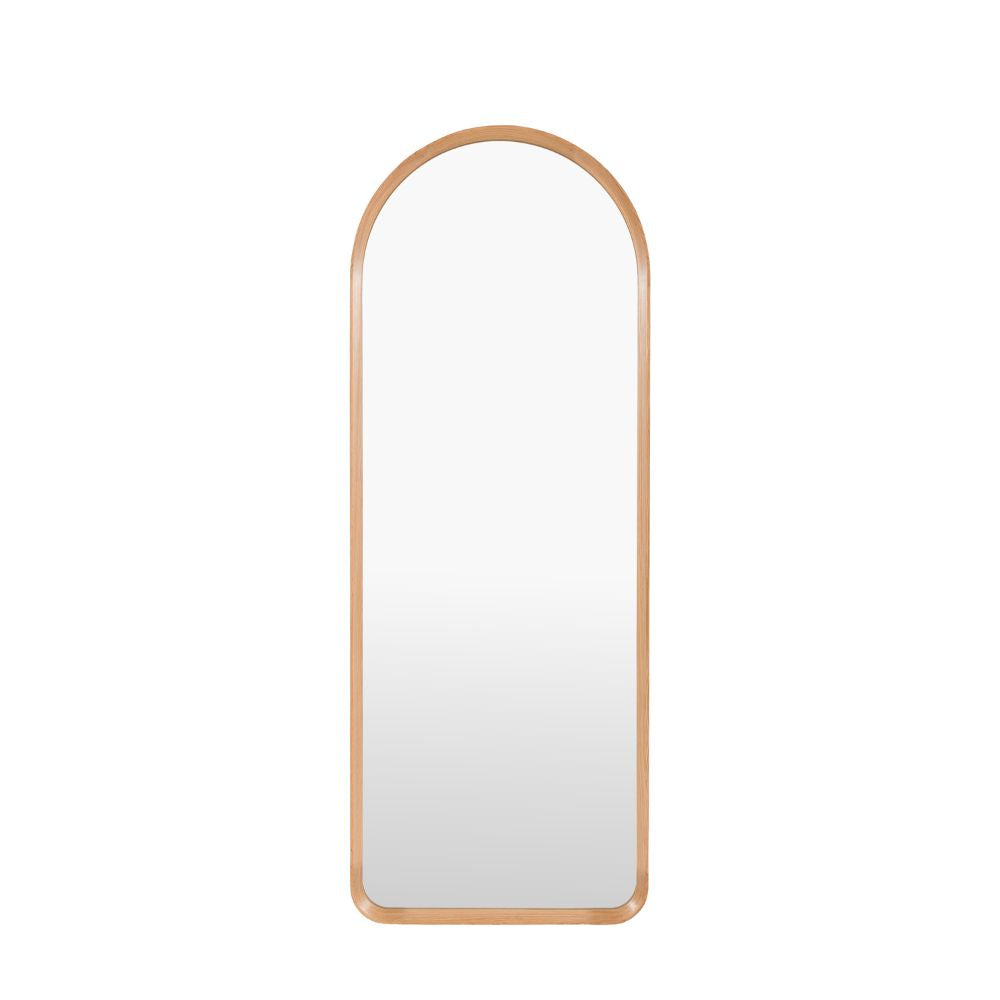 Minimalist arched full length mirror with a slim natural oak wooden frame isolated on a light grey background.