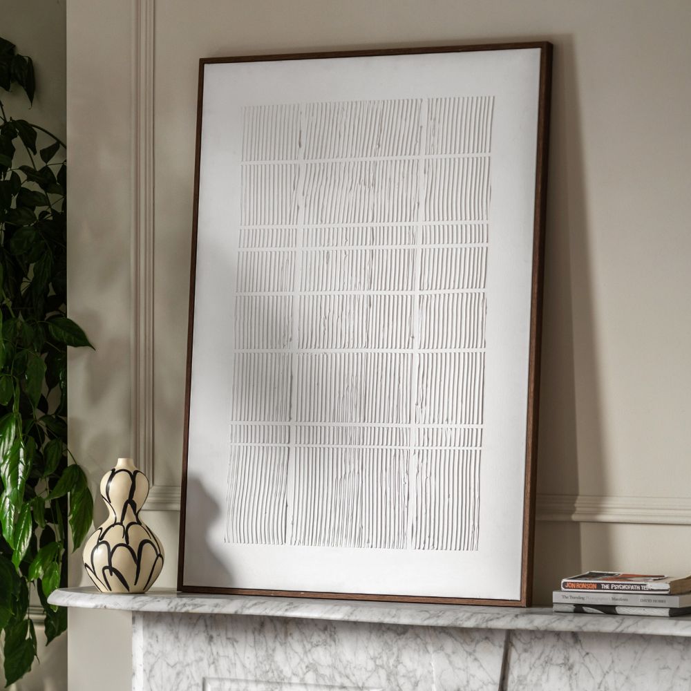 Close-up detail of textured white canvas artwork with raised linear design and slim dark wood frame.