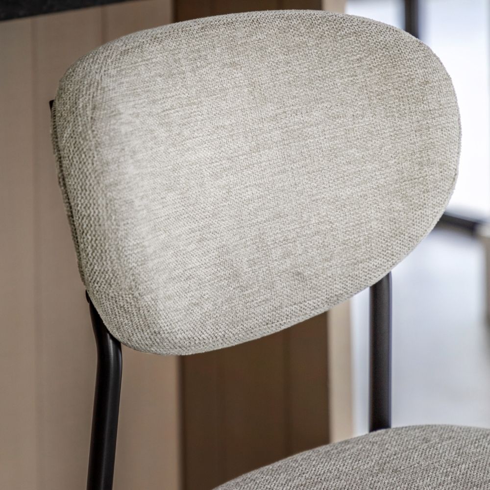 Close-up of a natural fabric bar stool backrest highlighting the soft woven texture and curved design with black metal supports.