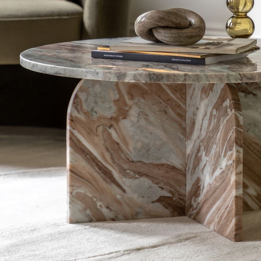 Close up of sculptural marble base with curved edges showing natural veining and polished finish.