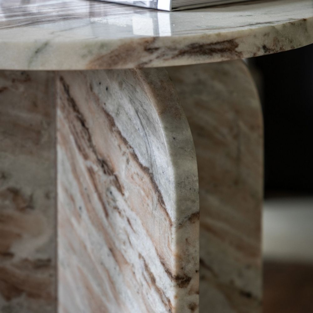 Close up of sculptural marble base showing curved edges and natural veining detail in neutral tones.