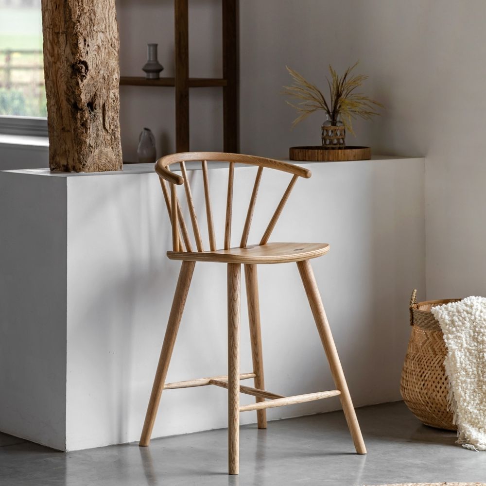 Natural oak spindle back wooden bar stool placed in a minimalist interior with neutral décor and soft natural lighting.