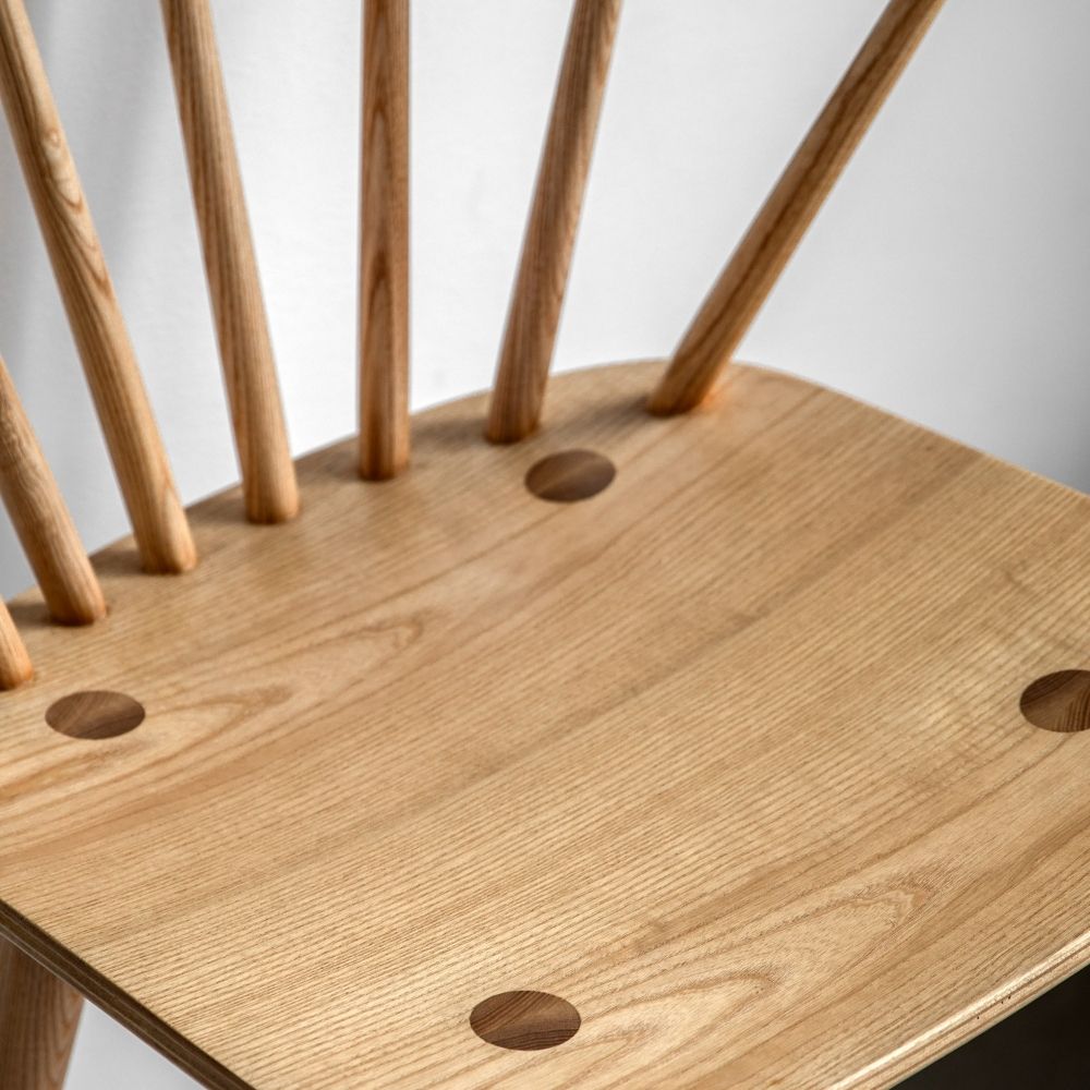 Detailed close-up of natural oak bar stool seat showing wood grain, smooth finish and joinery with spindle supports.