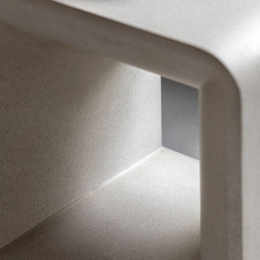 Close up of neutral concrete side table showing smooth curved edges and fine textured glass fibre reinforced surface.