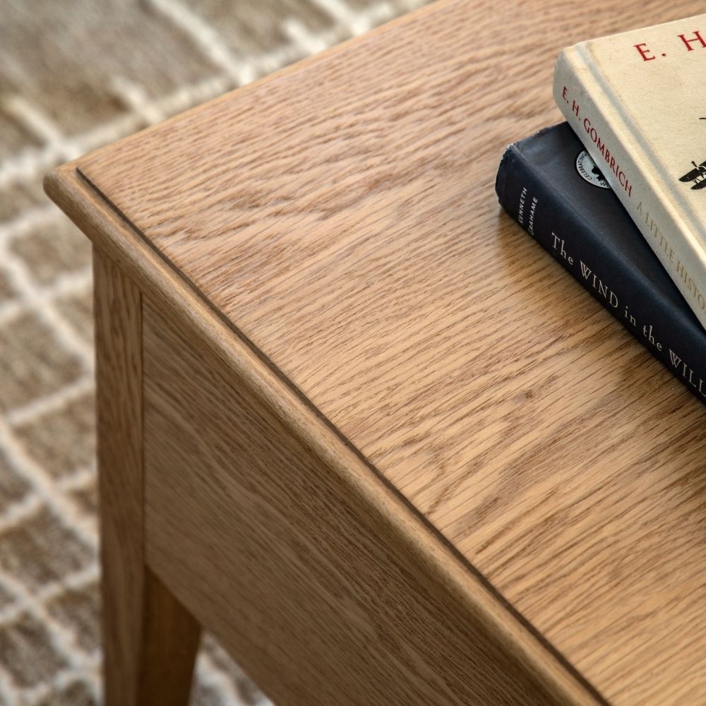 Detailed view of oak coffee table top showing natural wood grain texture and smooth finished edges with books on top.