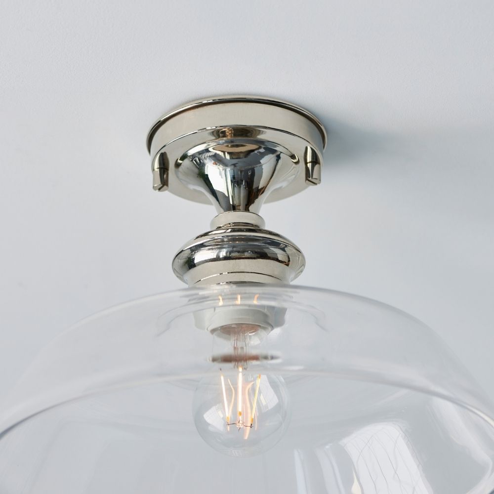 Polished nickel glass dome flush ceiling light installed on a ceiling, providing soft ambient lighting in a contemporary room.