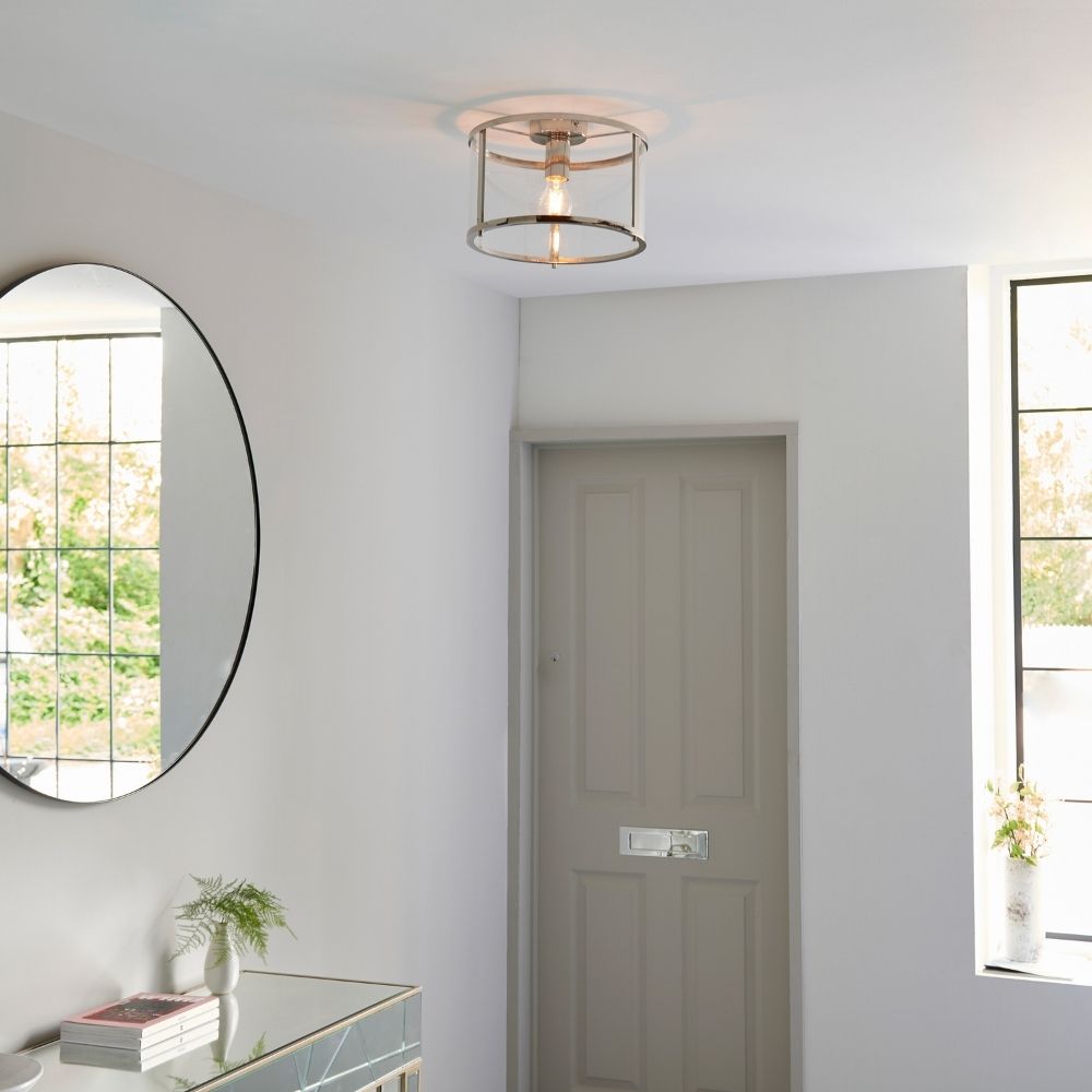 Polished nickel glass flush ceiling light installed in a contemporary hallway with mirror, door and natural light.