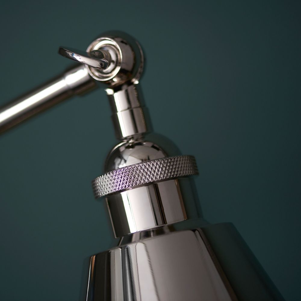 Close up of polished nickel adjustable lamp arm joint showing sleek metal finish and precision engineering.