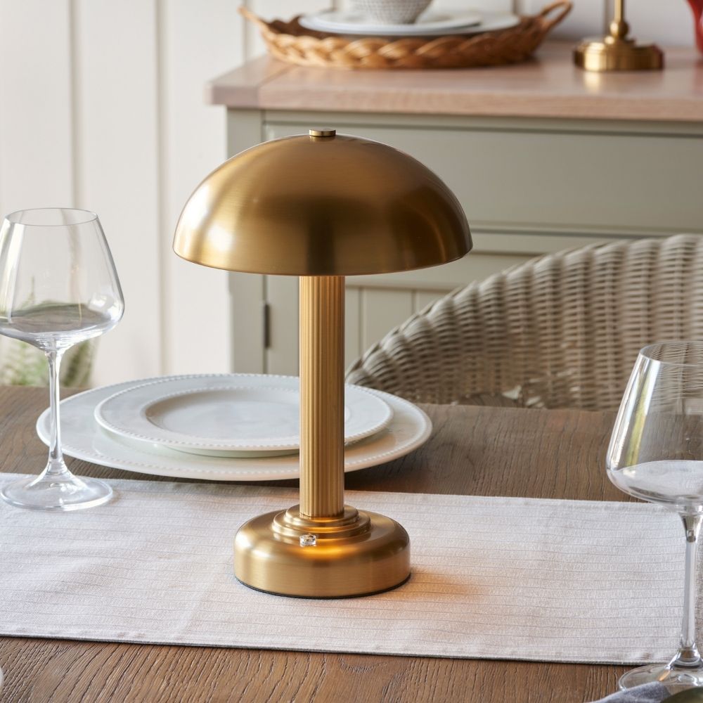 Rechargeable brass touch dimmer table lamp with dome shade shown on dining table and outdoor setting, featuring wireless design and warm ambient lighting.