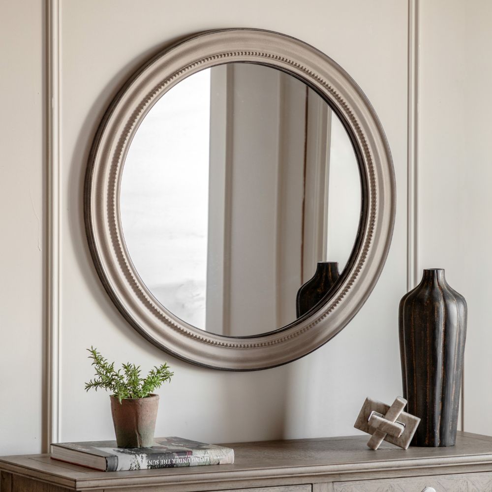 Round wall mirror with a distressed grey frame and decorative beaded detailing isolated on a light grey background.