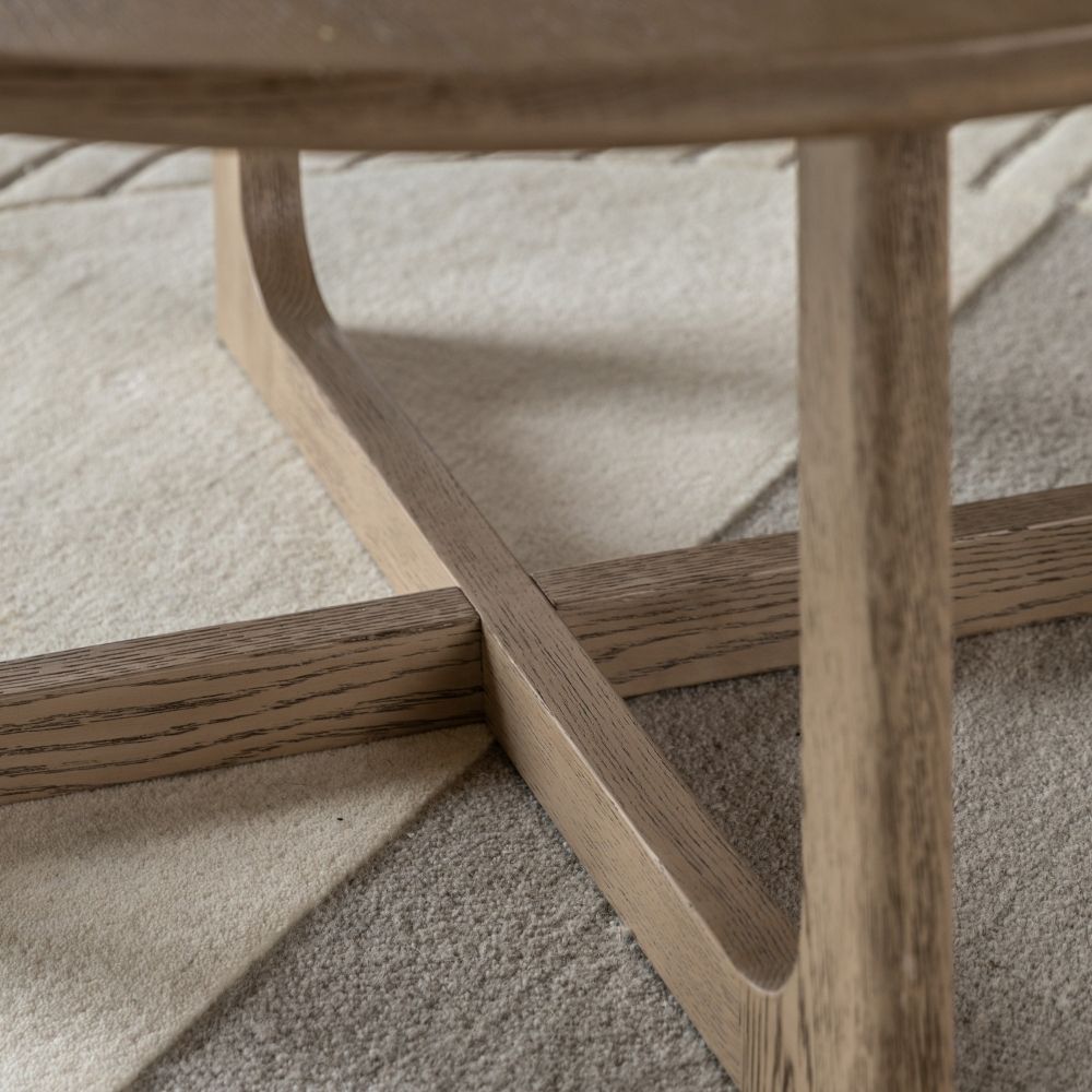 Detailed view of smoked oak coffee table base with intersecting supports and curved frame on a soft rug.