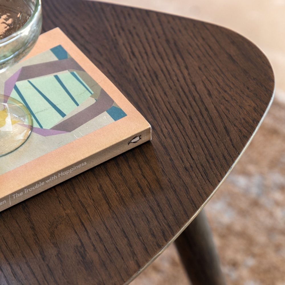Close up of smoked oak tabletop showing rich wood grain texture and smooth curved triangular edges.