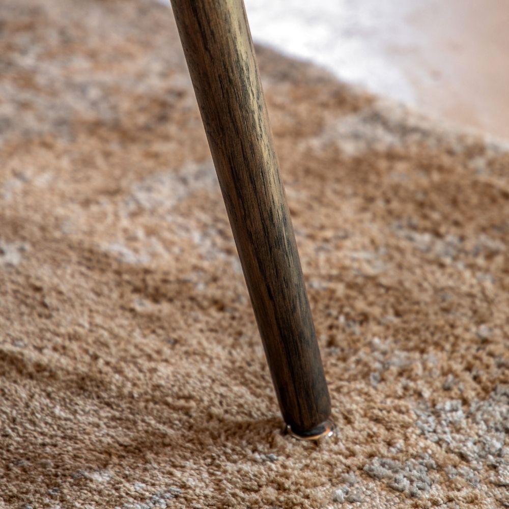 Close up of tapered oak leg on textured rug highlighting natural wood grain and sturdy construction.