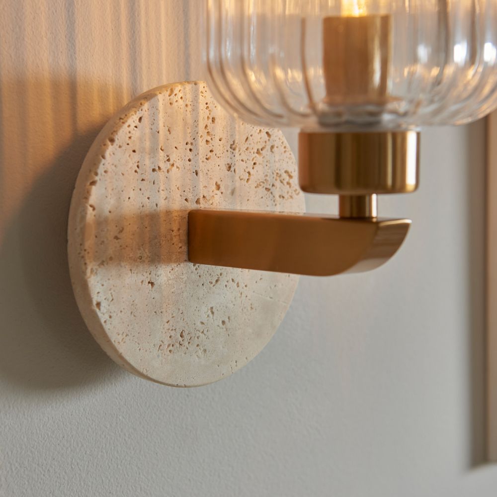 Detailed view of a textured stone backplate paired with a brushed brass arm on a modern decorative wall light.