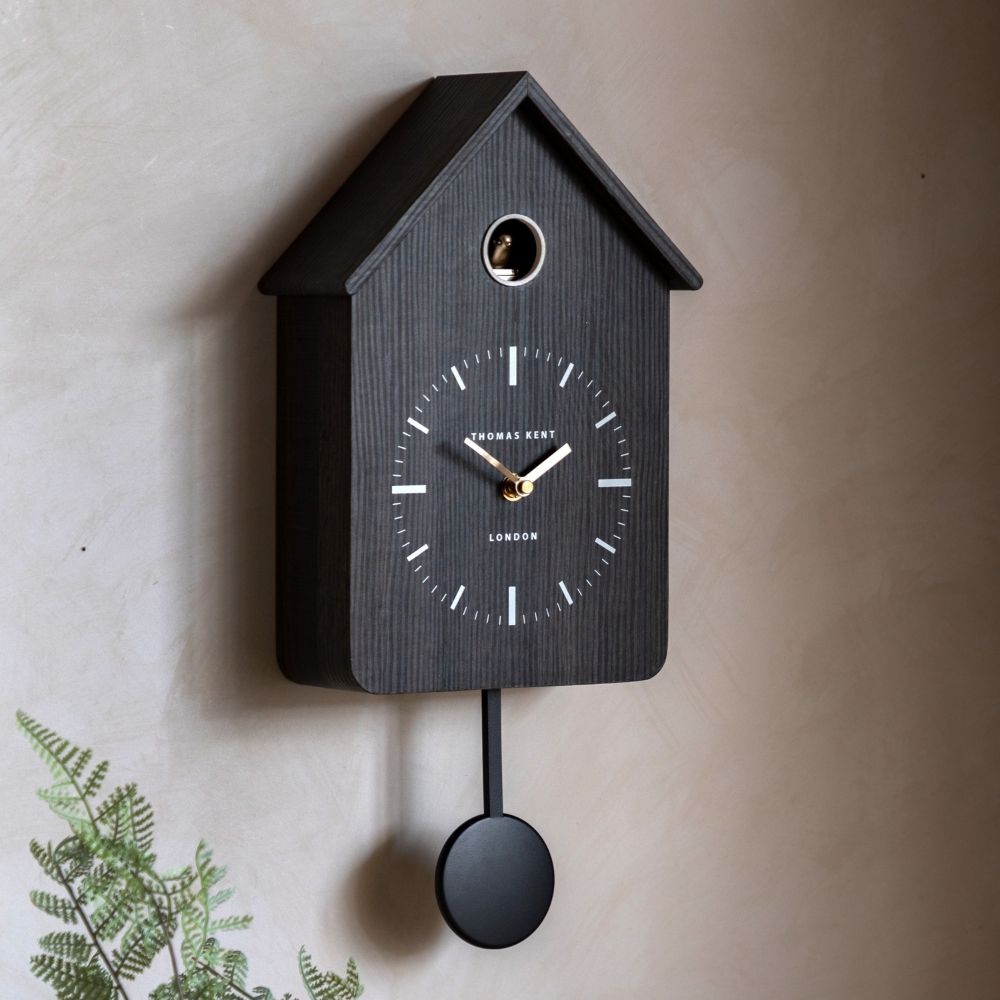 Thomas Kent charcoal cuckoo wall clock with gold hands and black pendulum styled on a neutral interior wall