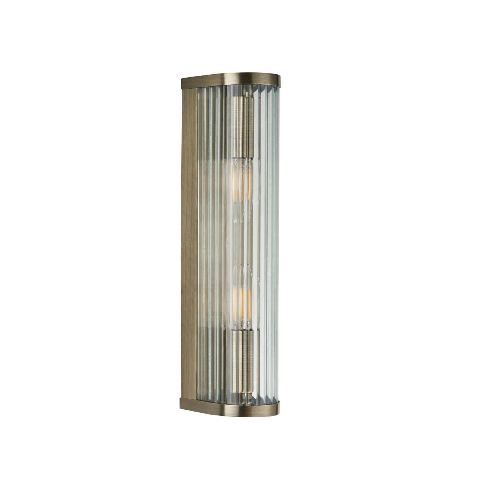 Vertical brass wall sconce featuring fluted glass panels, slim contemporary styling, and elegant exposed filament bulbs.