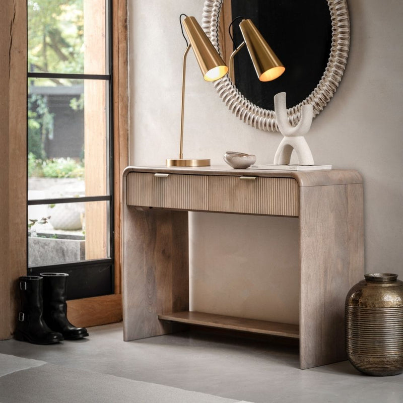 Walnut console table with two drawers and fluted fronts styled in a modern hallway with decorative lighting and accessories.