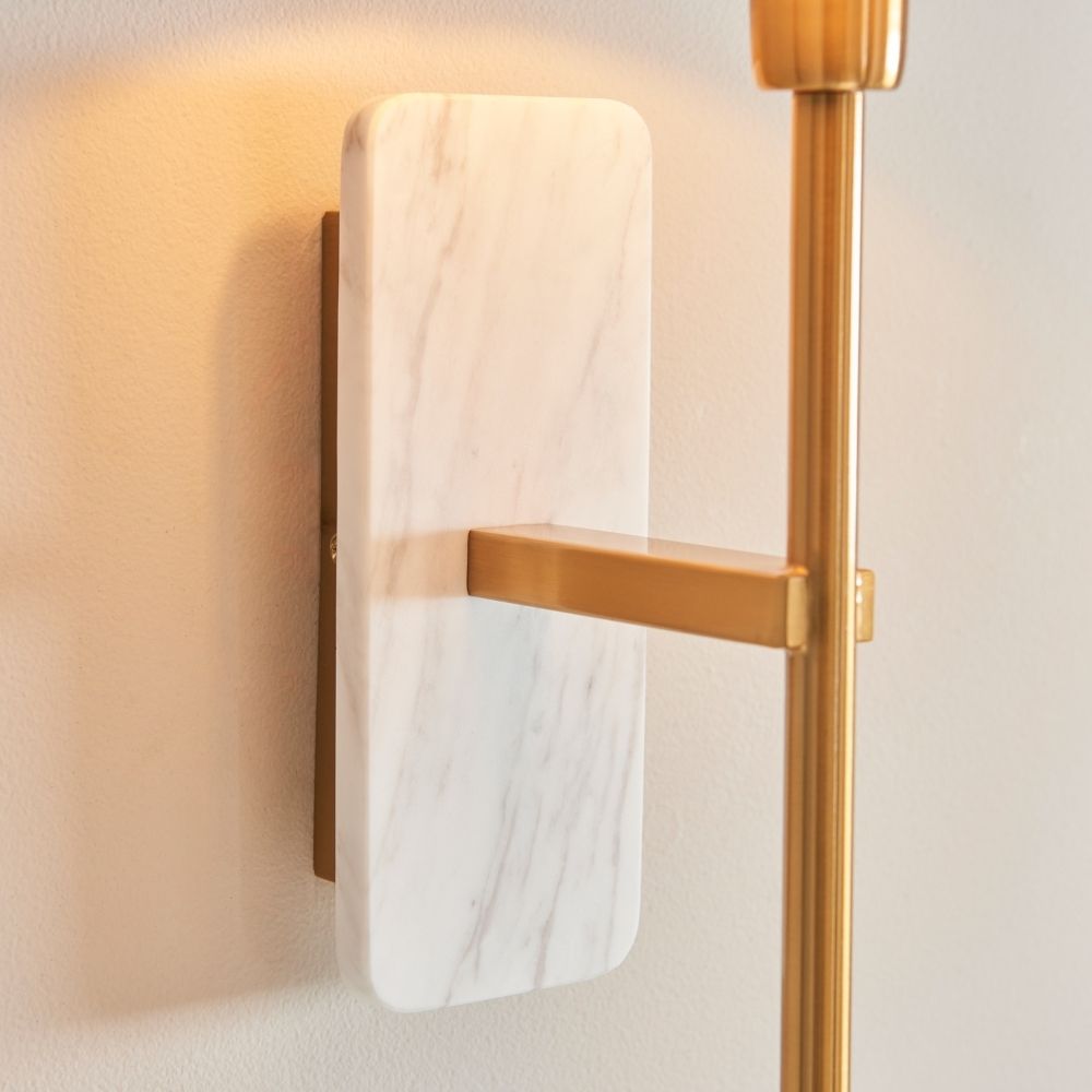 Detailed view of smooth white marble backplate with subtle veining and attached brushed brass arm on wall light.
