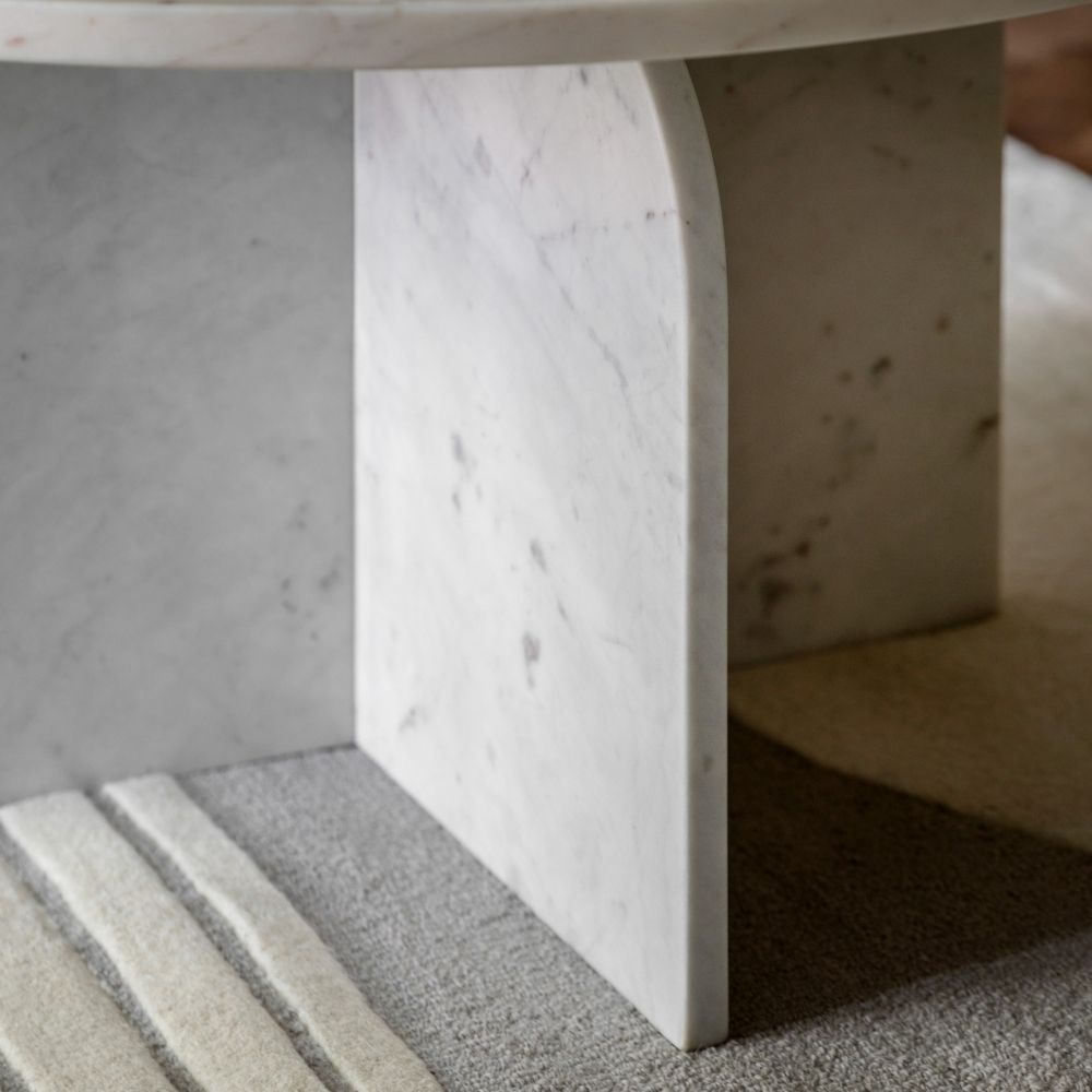 Close up of sculptural white marble base with curved edges showing subtle veining and polished finish.