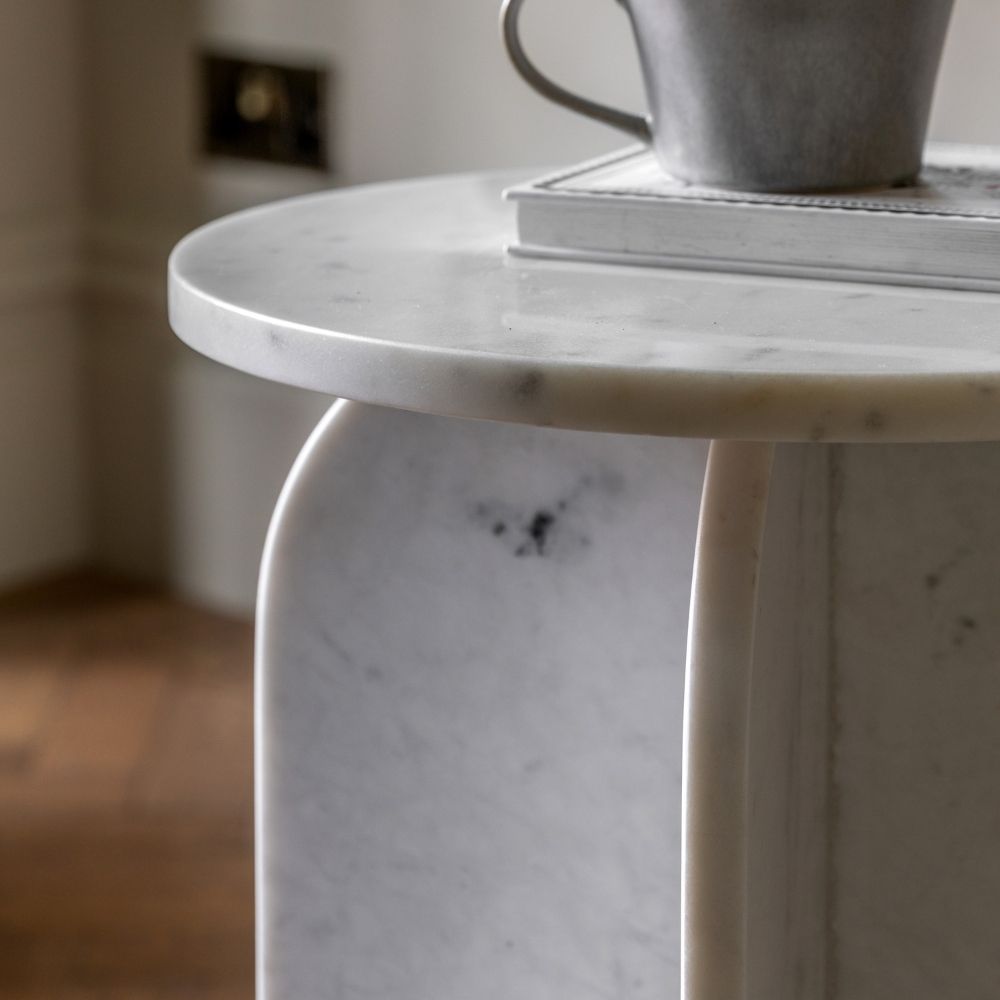 Close up of sculptural marble base showing curved edges and subtle natural veining in soft white and grey tones.