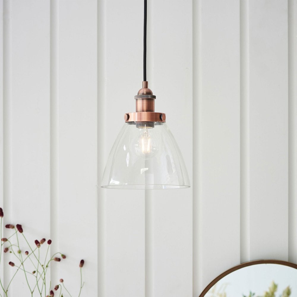 Modern copper ceiling pendant light with a transparent glass shade, creating a warm and ambient glow.
