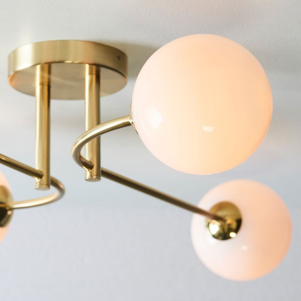 Elegant mid-century-inspired ceiling light featuring a warm brass finish and an opal glass shade for a soft glow.
