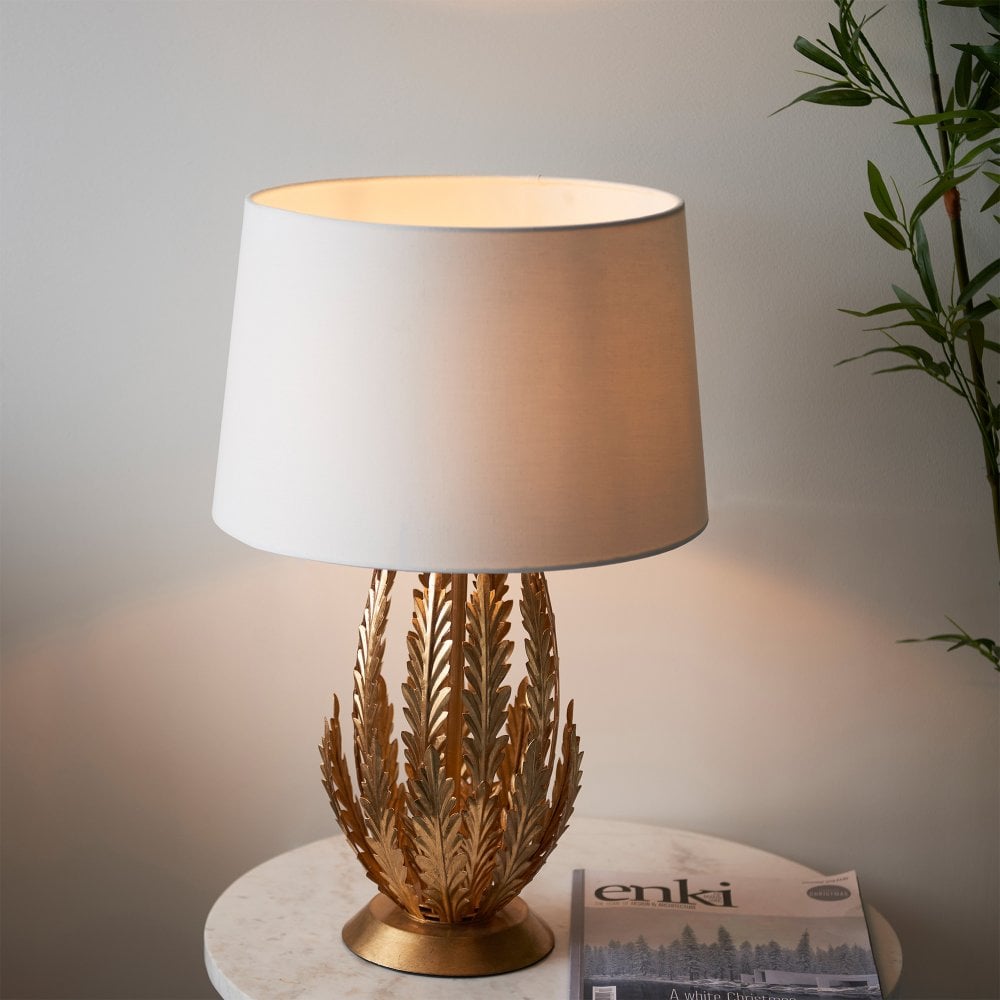 Elegant gold palm leaf table lamp with a fabric shade, designed to bring a luxurious and sophisticated touch to your living space.
