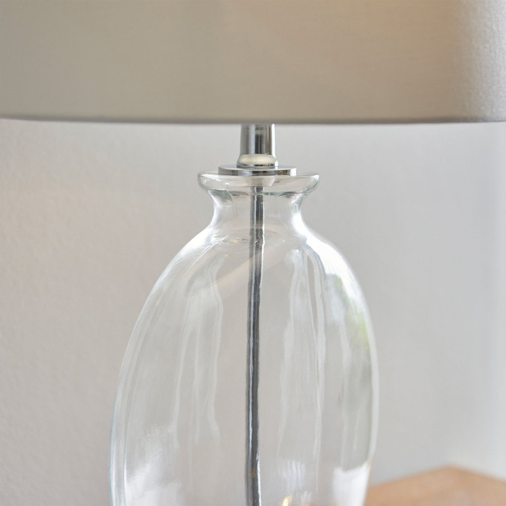 Timeless glass lamp featuring a sleek silhouette and a white linen shade, ideal for both modern and traditional interiors.
